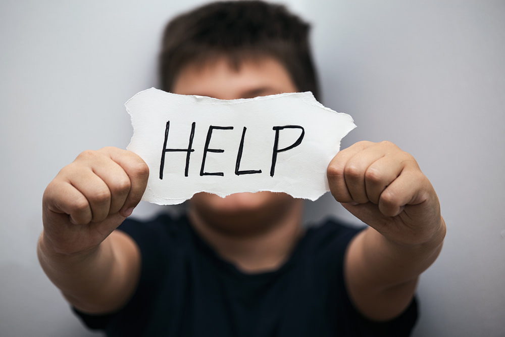 chico con un cartel de help o ayuda